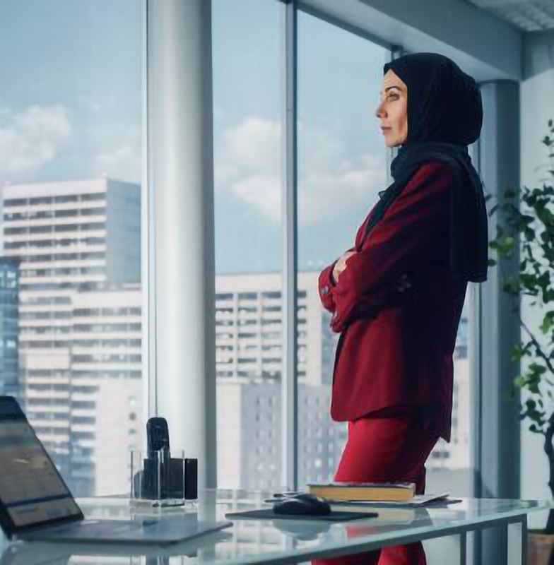 Businesswoman looking out of the window of her office at highrises