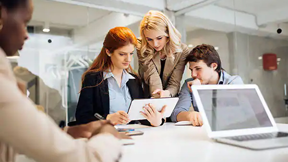 A group of young corporate officials working on a tab and discussing