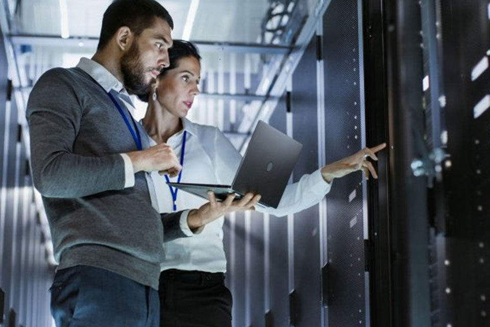 Two people in a data centre working on a laptop