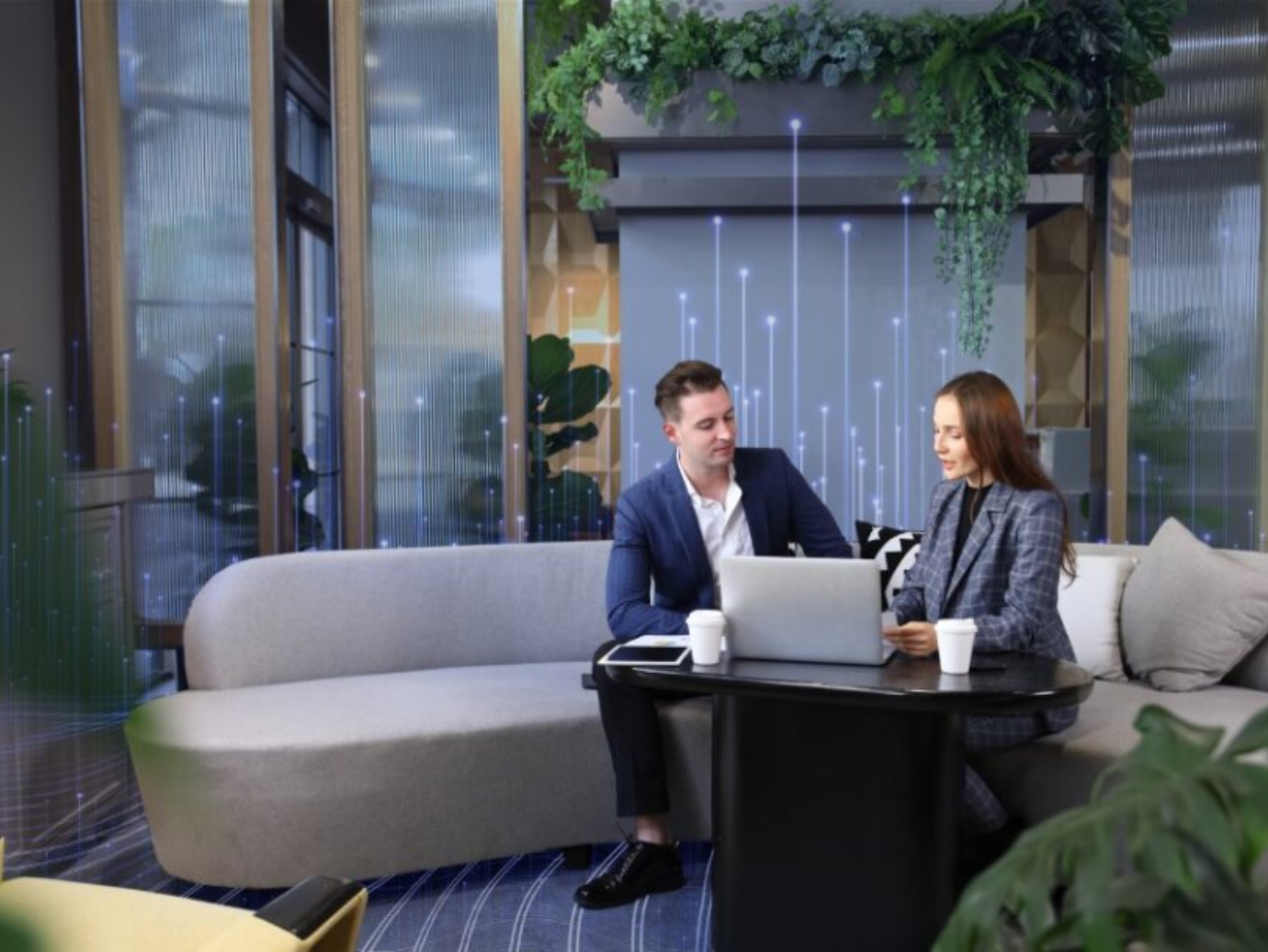 A man and woman sitting on a sofa and looking at a laptop in an office building