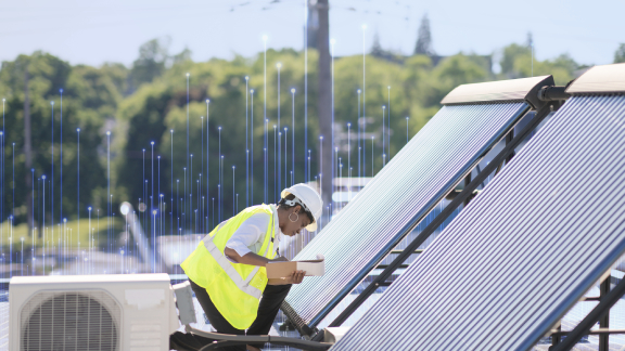 A female engineer writing on a clipboard near a set of solar panels