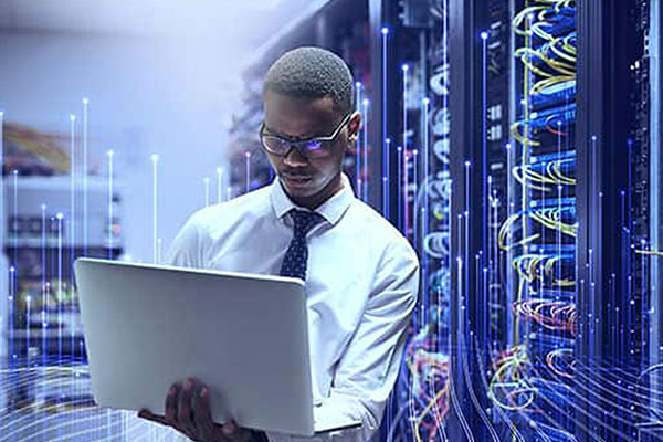 A man using a laptop while standing in a data center