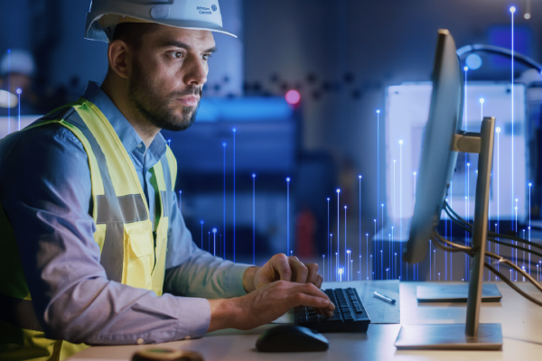 Johnson Controls technician using a desktop, overlaid with a graphic of transmission nodes in the background