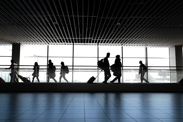 People with luggage walking across a moving walkway in an airport