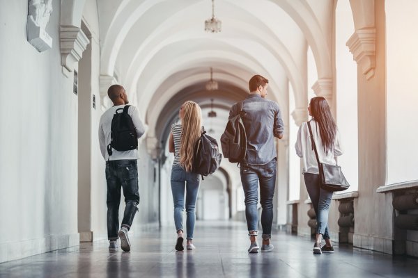 Rear view of university students walking along a hallway